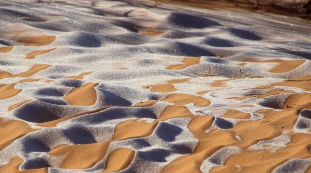 Snow dusting orange sand dunes near Ain Sefra in the Algerian Sahara