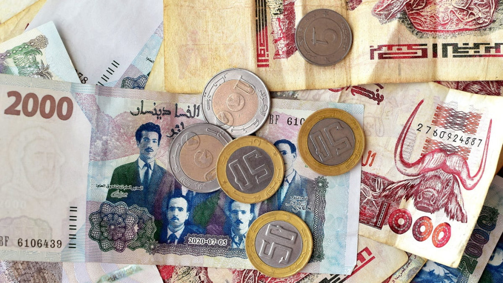 Algerian dinar banknotes and coins spread out on a table