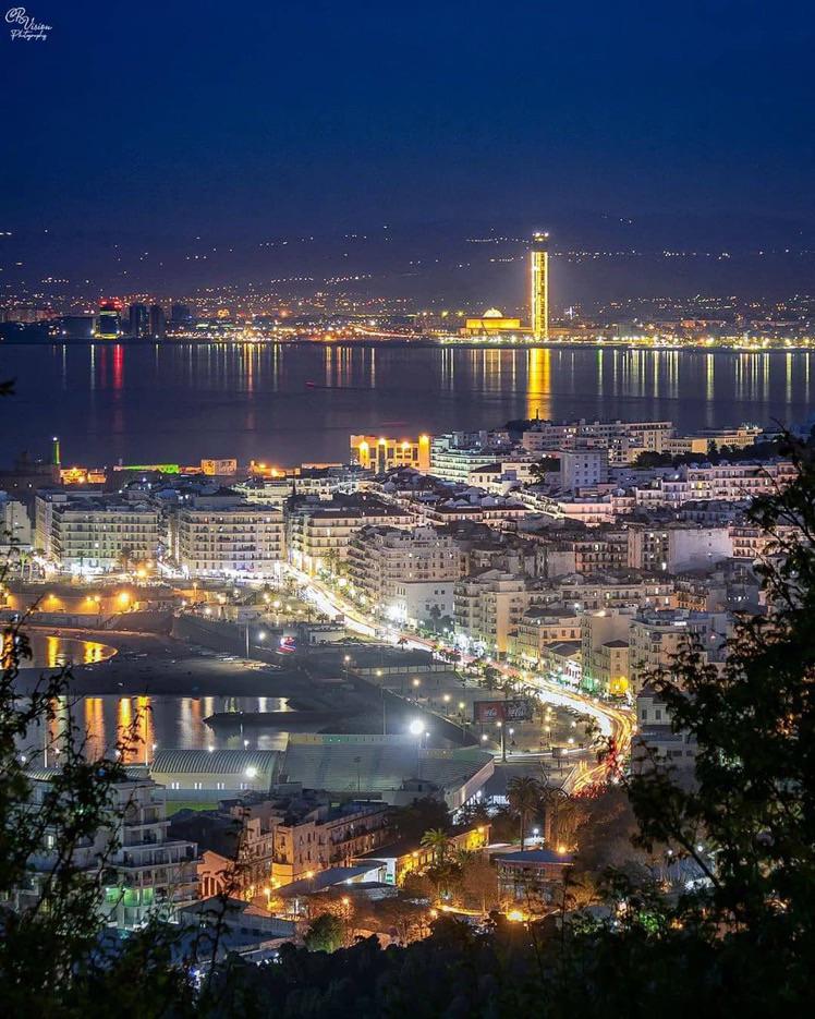 Algiers at night with the lit Great Mosque minaret across the bay