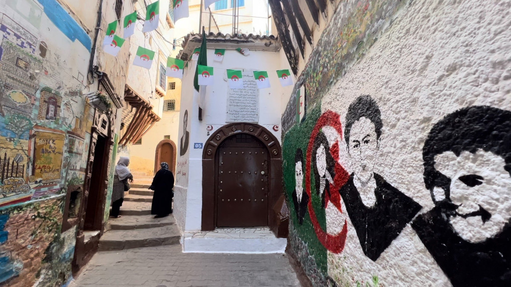Casbah alley in Algiers with flag bunting and a mural of independence heroes