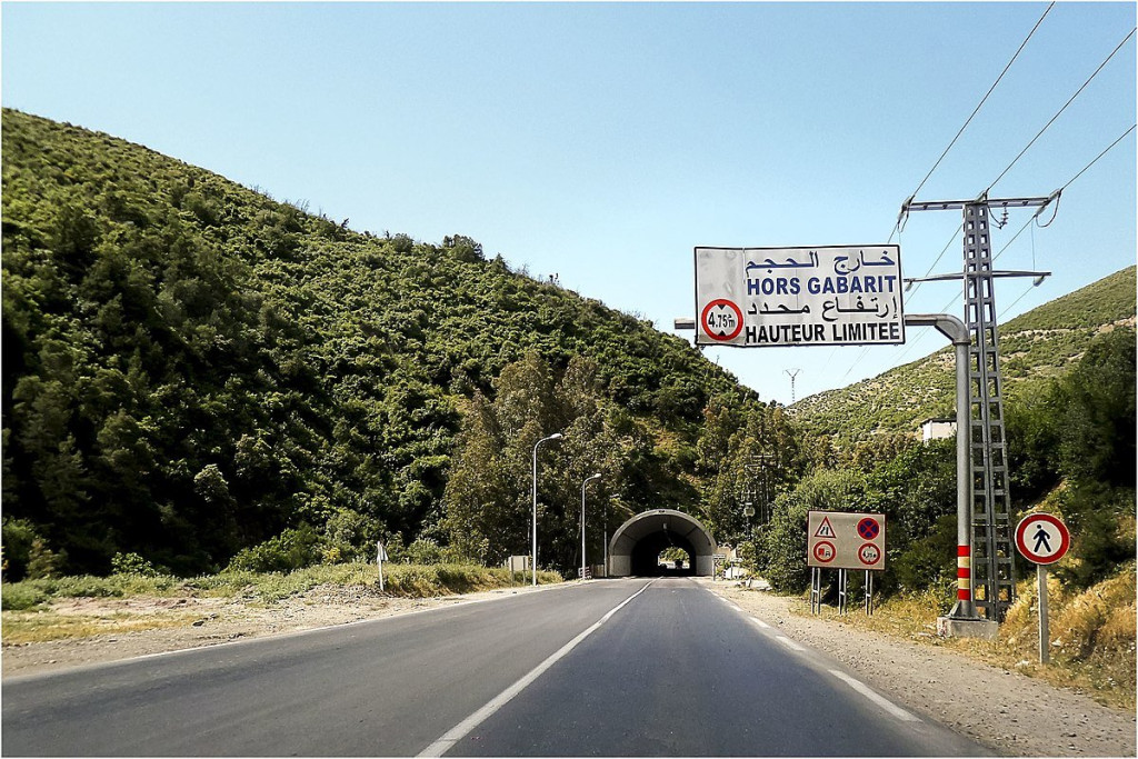 Road tunnel at El Khemis with a height limit sign on wooded hills