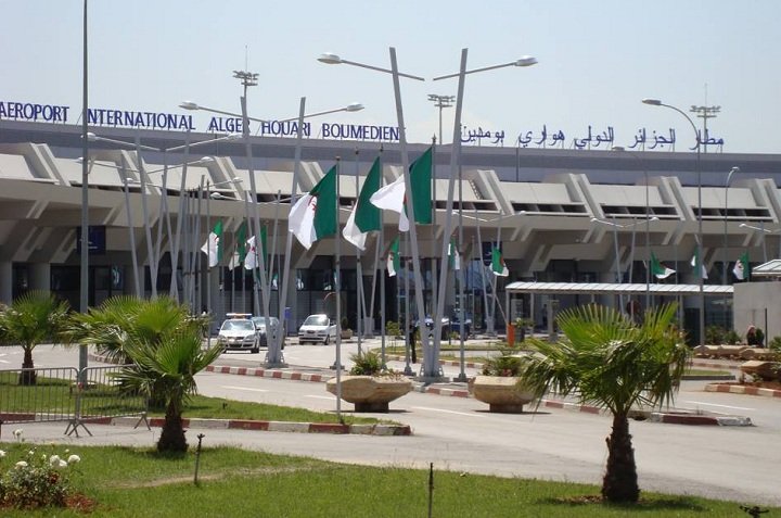Algiers Houari Boumediene International Airport terminal with Algerian flags at the entrance