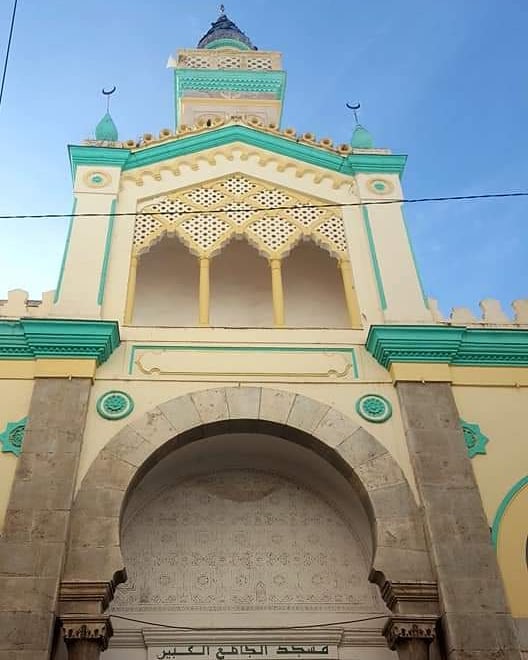 Arched entrance and green and cream facade of the Grand Mosque of Constantine