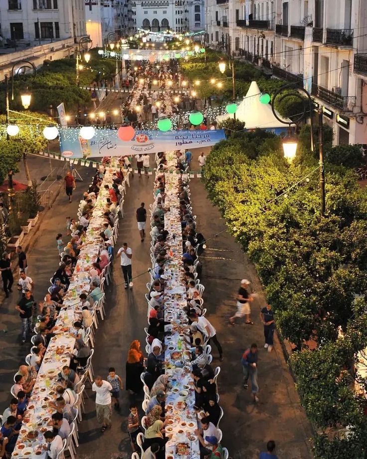 Long communal iftar tables set along a lantern-lit city street during Ramadan