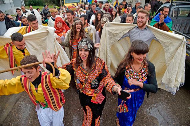 Young people in colorful Kabyle dresses celebrating Yennayer, the Amazigh new year, in a crowded street