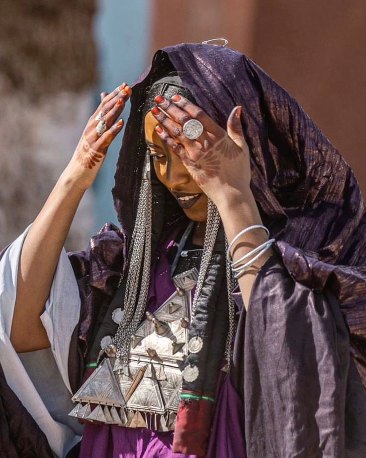 Tuareg woman in a purple veil wearing large silver pendants and henna on her hands
