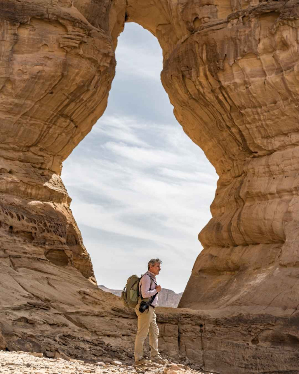 Backpacker with camera visiting eroded monoliths in AlUla Saudi Arabia