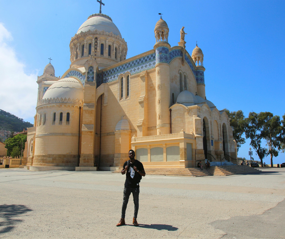 Man in dark clothes standing in front of Notre-Dame d'Afrique basilica in Algiers