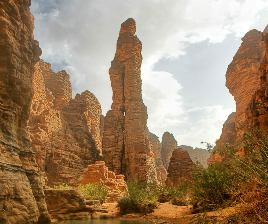Tall sandstone spire and canyon walls above a small pool in Essendilène Canyon