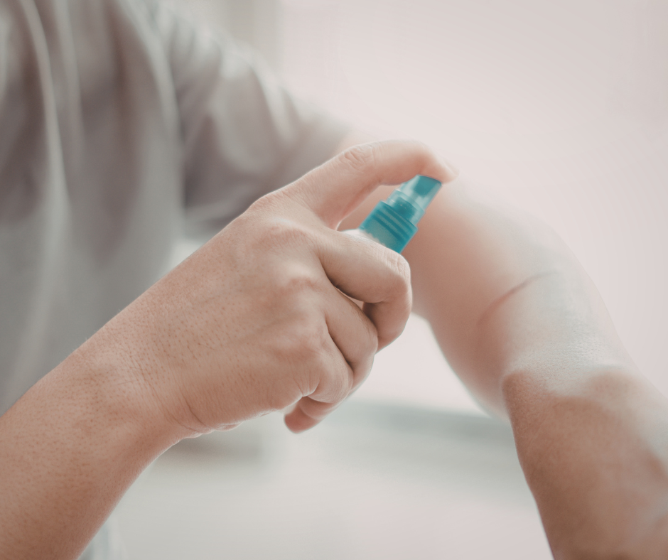 Person spraying sunscreen or insect repellent onto their forearm