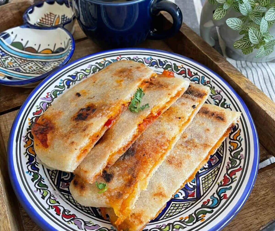 Golden pan-fried mahjouba flatbread filled with tomato and pepper on a painted plate