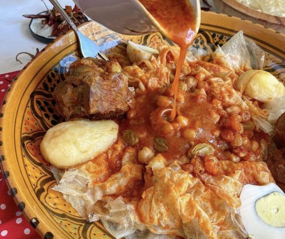 Chakhchoukha with torn flatbread, chickpeas and lamb in red sauce, served in a decorated bowl