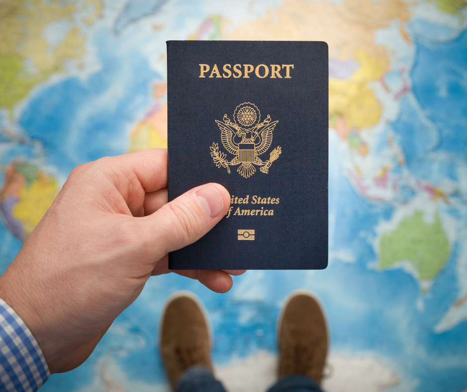 Hand holding a US passport over a colorful world map