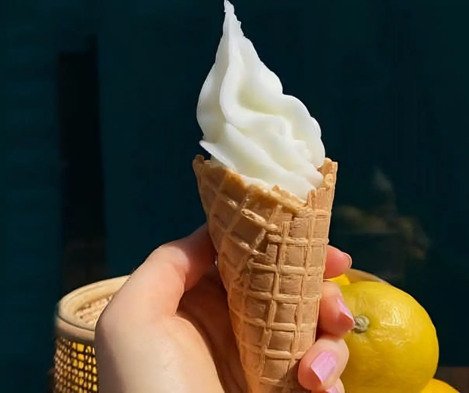 Soft ice cream cone held beside fresh lemons