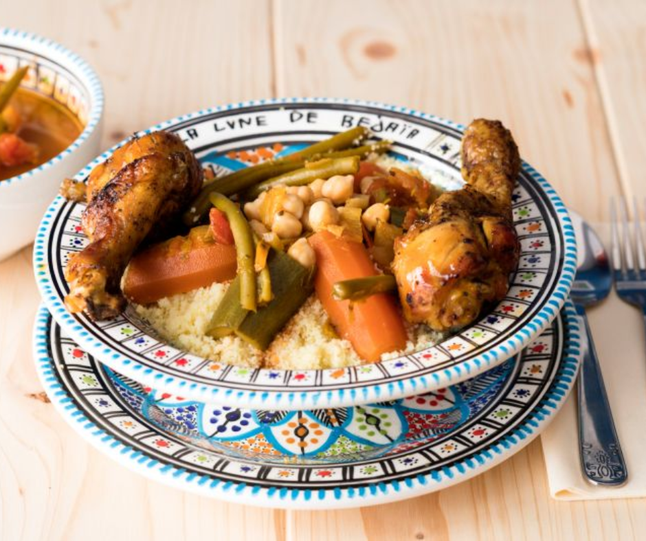 Plate of couscous with roast chicken, carrots and chickpeas on a blue patterned dish