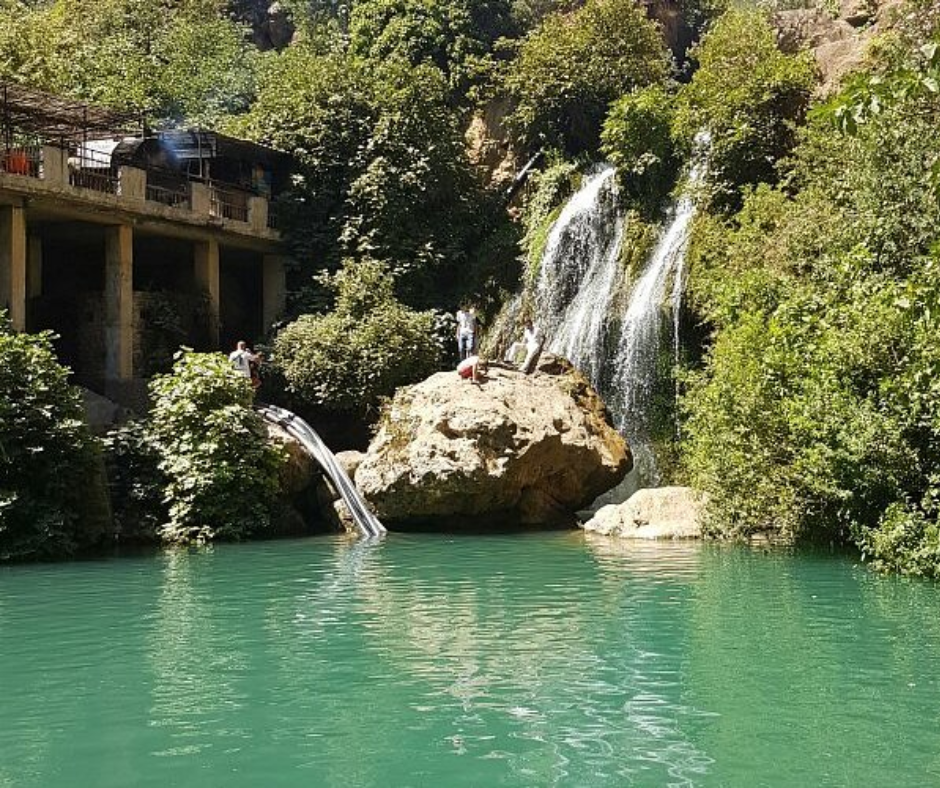 Waterfall dropping into a turquoise pool in a wooded gorge near Tlemcen