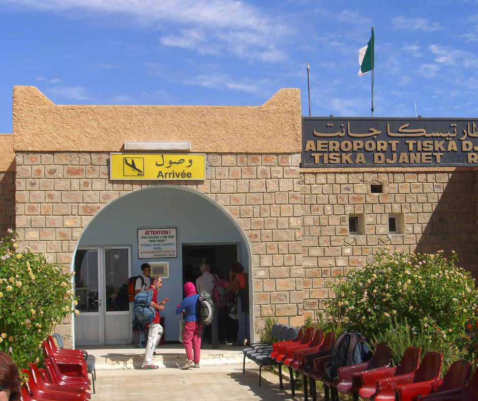 Arrivals entrance of Tiska airport in Djanet with travelers outside and the Algerian flag