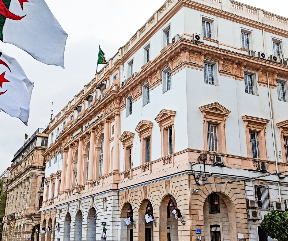 Ornate colonial-era building with Algerian flags on a street in Algiers