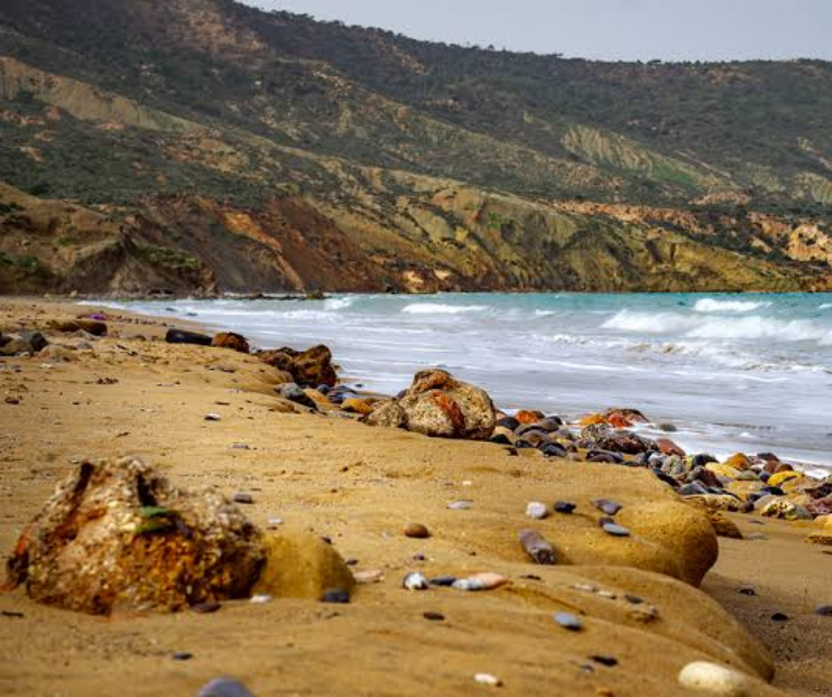 Rocky beach with colorful pebbles and eroded hills at Ain Franin