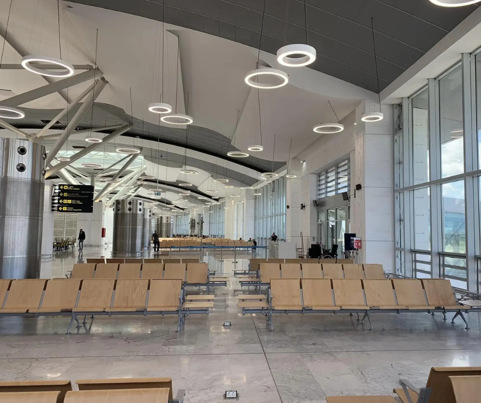 Empty waiting hall with wooden benches and ring lights at Oran airport