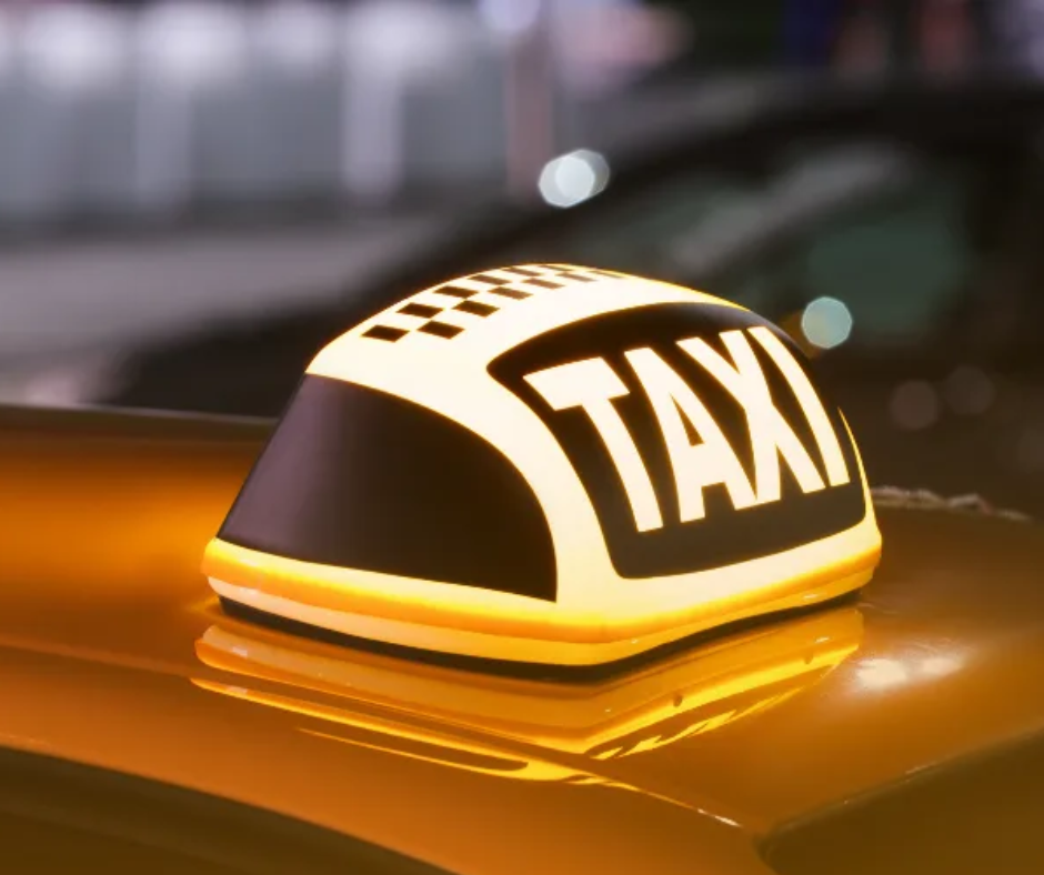 Glowing taxi sign on the roof of a yellow car at night