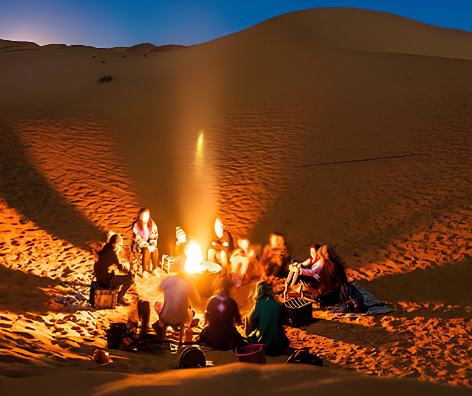 People gathered around a campfire on a sand dune at night